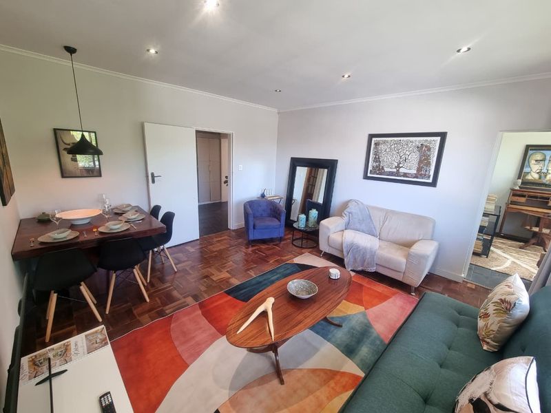 An open-plan living and dining area featuring classic parquet flooring and modern recessed downlighting, creating a warm and inviting atmosphere.