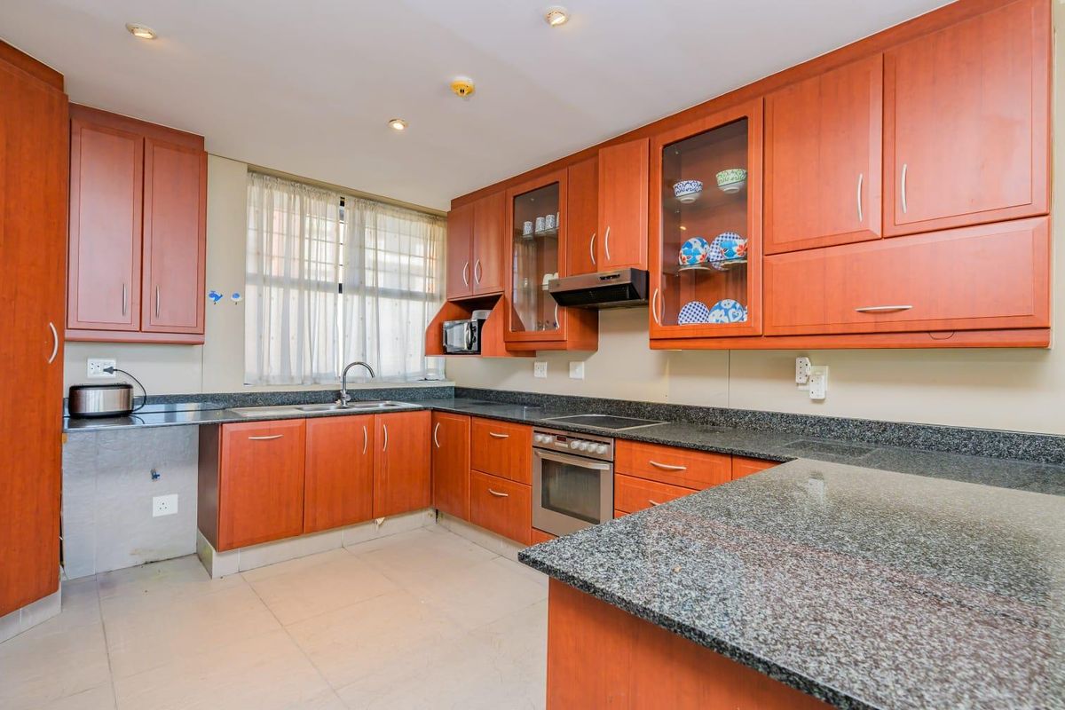 A functional kitchen featuring cherry wood cabinetry, granite countertops, a built-in oven, and an electric hob with an extractor fan.