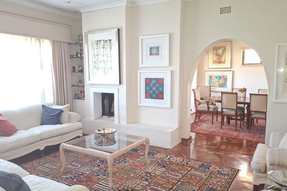 Spacious living room featuring a classic fireplace, elegant parquet flooring, and a charming arched entryway leading into the adjacent dining area.