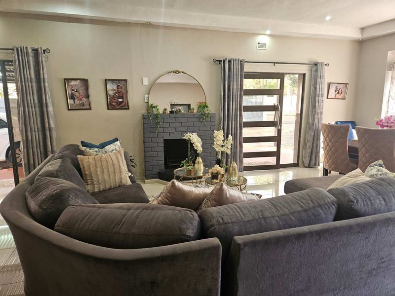 A comfortable living room featuring a central brick fireplace, tiled flooring, and large sliding glass doors that provide natural light and access to the exterior.