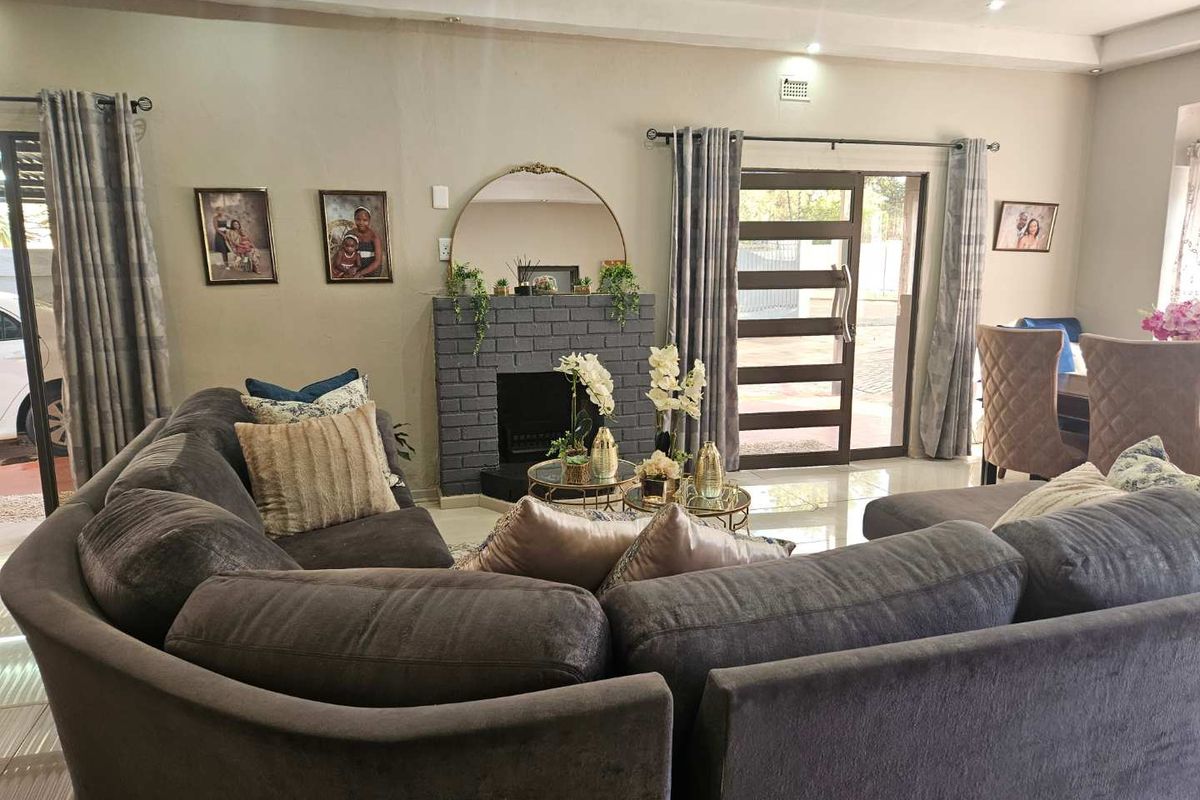 A comfortable living room featuring a central brick fireplace, tiled flooring, and large sliding glass doors that provide natural light and access to the exterior.