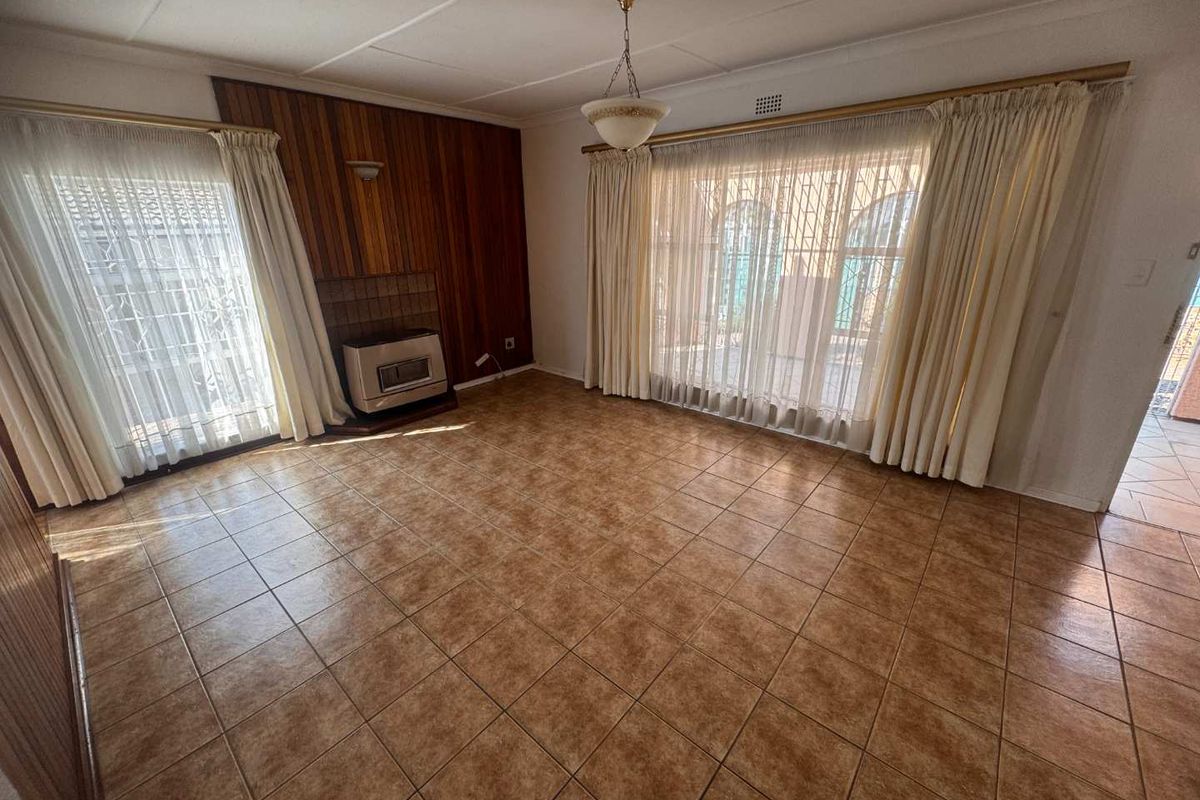Spacious living room featuring tiled flooring, wood paneling, and a built-in fireplace, with large sliding doors providing access to the outdoor area.
