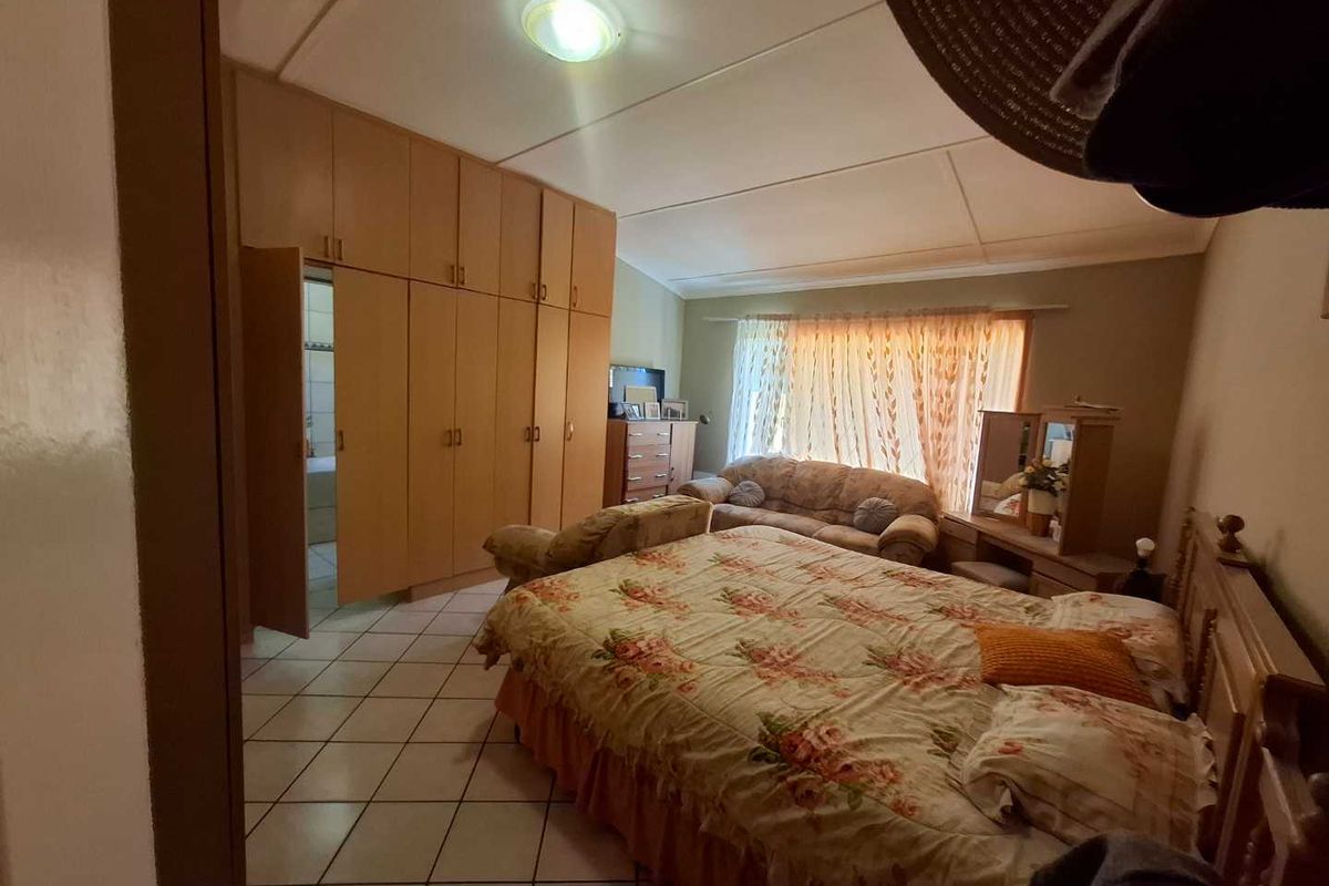A bedroom featuring built-in wooden cabinetry and tiled flooring, offering functional storage space and natural light through the window.