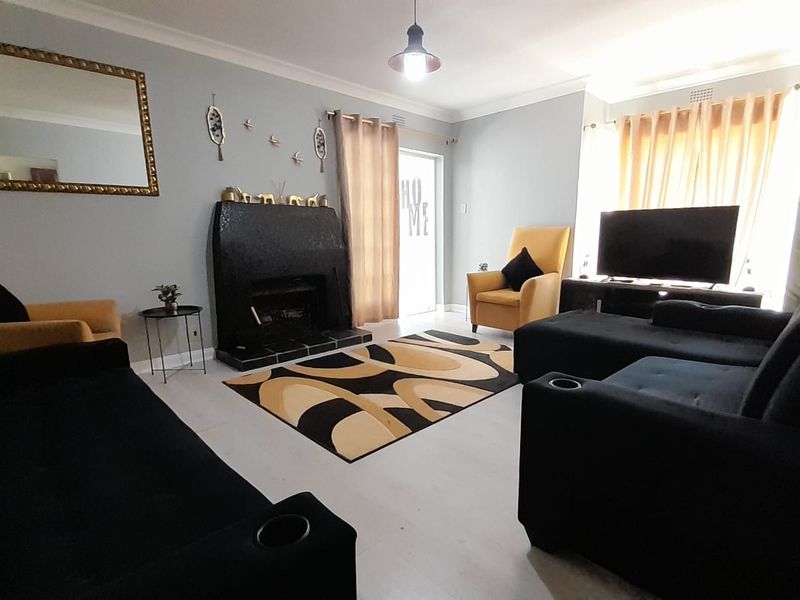 A comfortable living room featuring a prominent fireplace, tiled flooring, and decorative cove cornicing, providing a functional and inviting space.