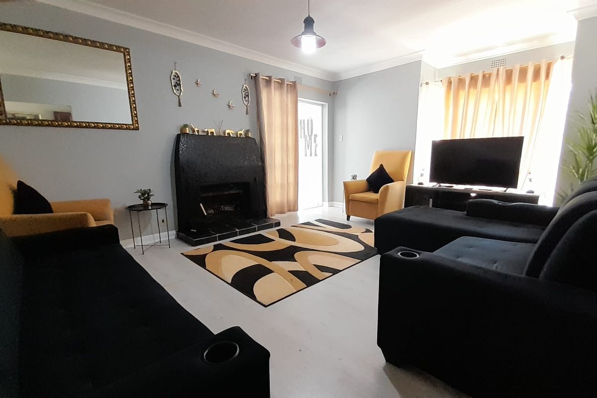 A comfortable living room featuring a prominent fireplace, tiled flooring, and decorative cove cornicing, providing a functional and inviting space.