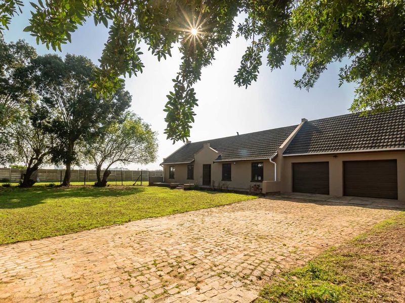A well-maintained small holding property featuring a spacious front garden, cobblestone driveway, and a double garage with a tiled roof.