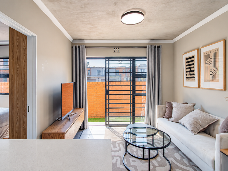 A bright living room featuring tiled floors, a modern ceiling light, and a sliding door providing access to an outdoor patio area.