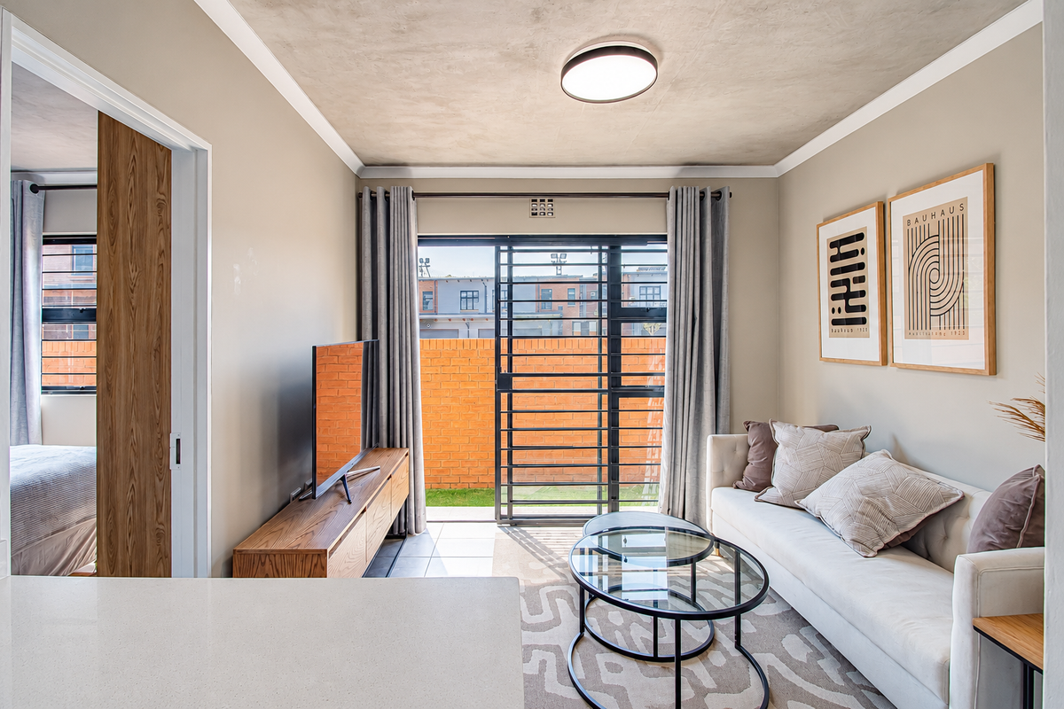 A bright living room featuring tiled floors, a modern ceiling light, and a sliding door providing access to an outdoor patio area.