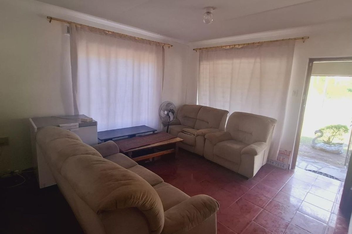 A living room featuring tiled flooring and direct access to the exterior, providing a functional space with natural light.