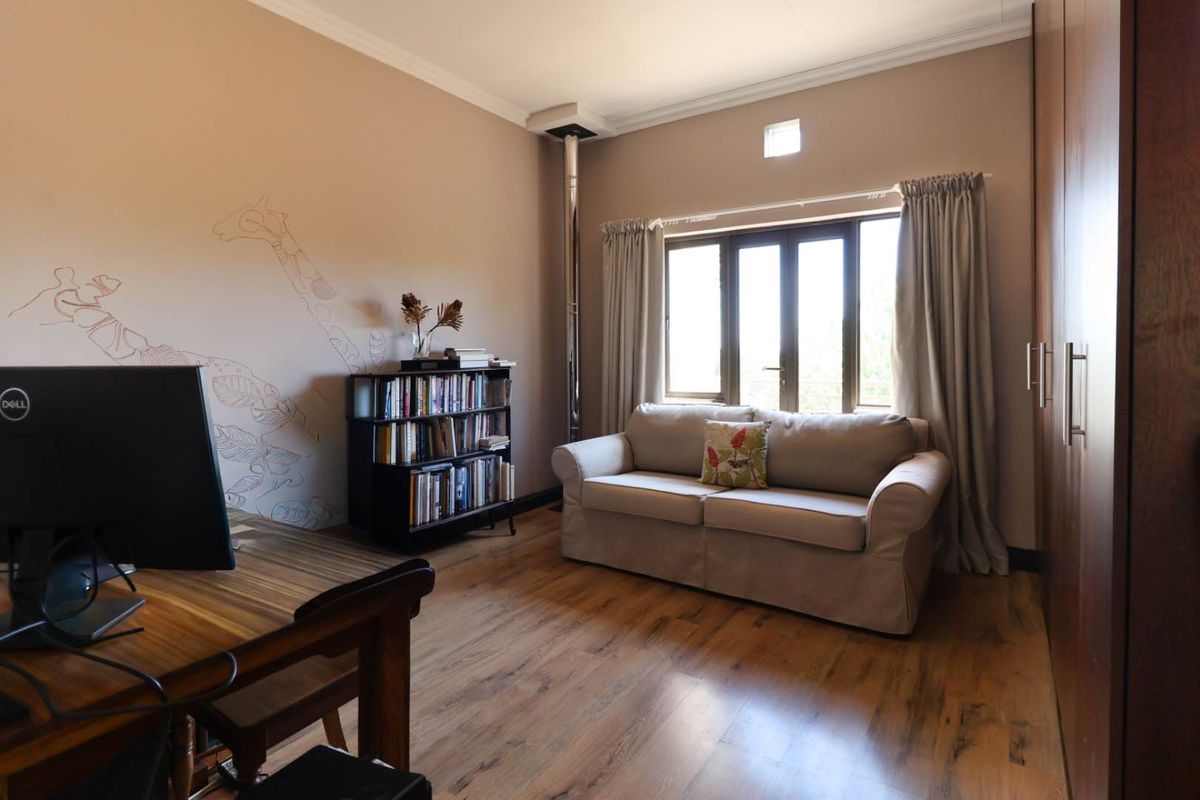 A versatile bedroom featuring wood-look flooring, built-in cupboards, and a fireplace flue, offering a comfortable space for rest or home office use.