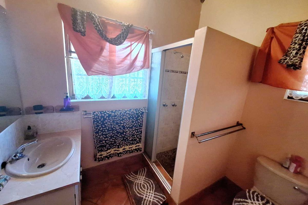 A functional bathroom featuring a built-in vanity with basin, a separate shower enclosure, and a toilet, finished with tiled flooring.