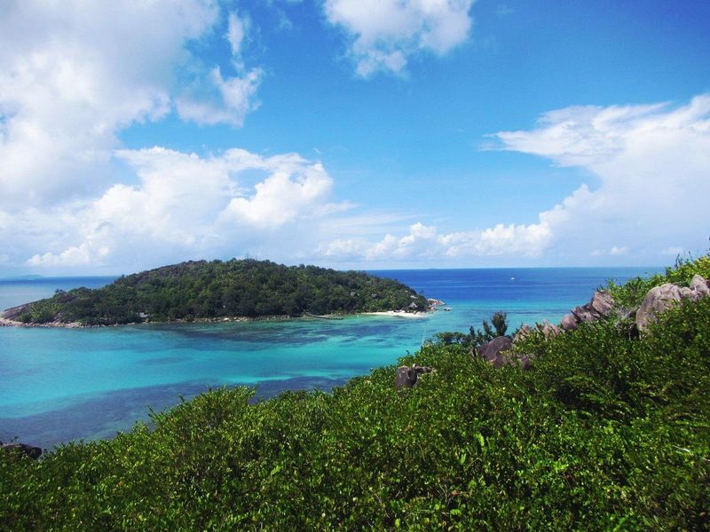 A scenic elevated view overlooking a tropical island, turquoise ocean waters, and lush coastal vegetation.