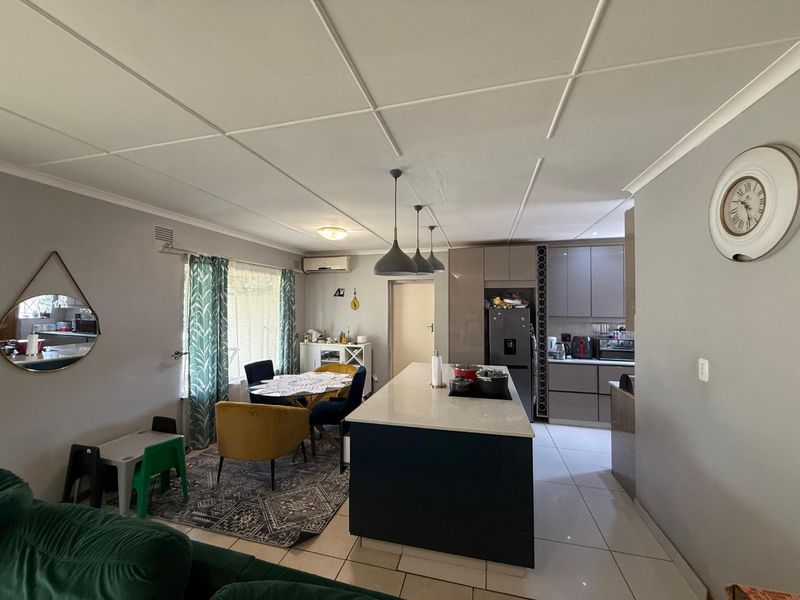 Open-plan living and kitchen area featuring a central island, modern cabinetry, tiled flooring, and split-system air conditioning.