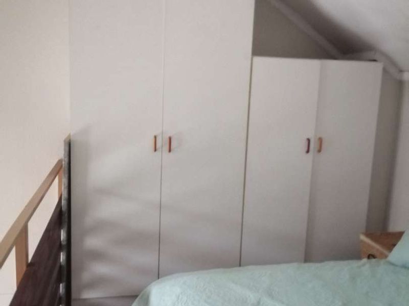 Bedroom featuring built-in white wardrobes and a sloped ceiling, with a wooden balustrade overlooking the lower level.