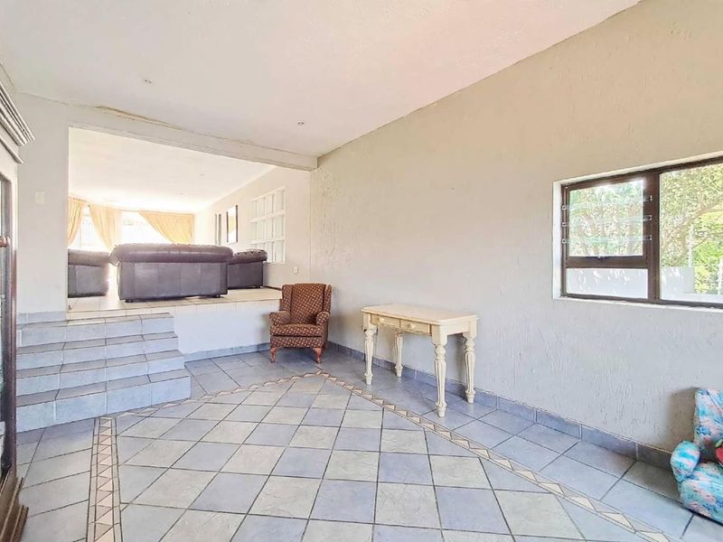 A split-level living area featuring tiled flooring, a stepped transition between levels, and a louvre window, offering a spacious layout for potential renovation.