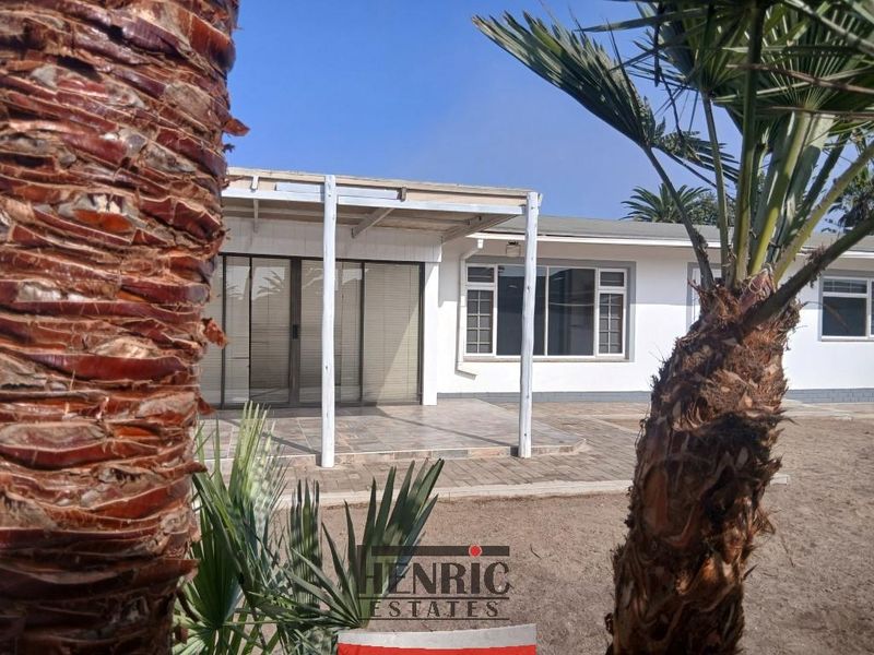 Rear view of the house featuring a covered patio area with tiled flooring, sliding glass doors, and a timber pergola structure.