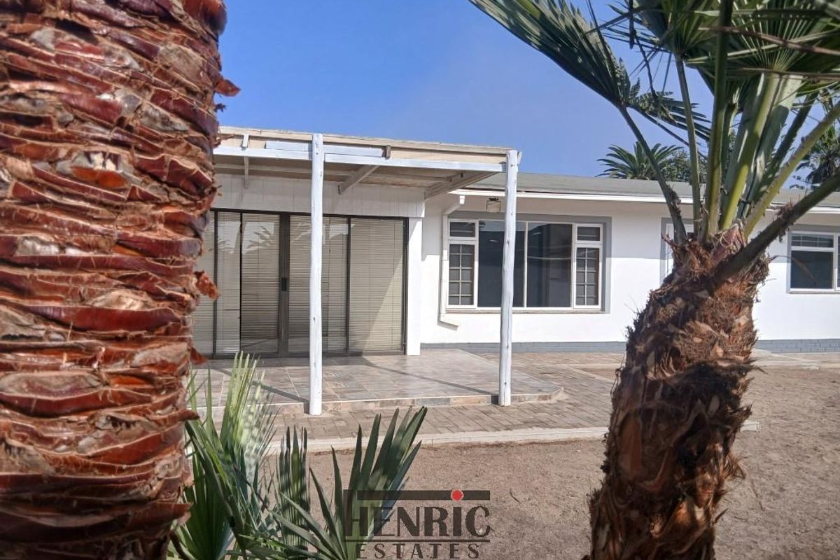 Rear view of the house featuring a covered patio area with tiled flooring, sliding glass doors, and a timber pergola structure.