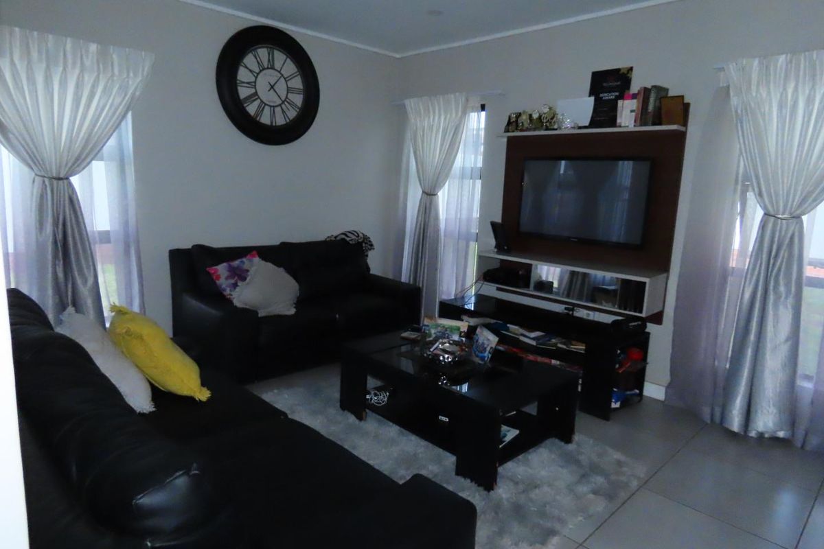 A comfortable living room featuring tiled flooring, neutral wall finishes, and a built-in media unit for television and storage.