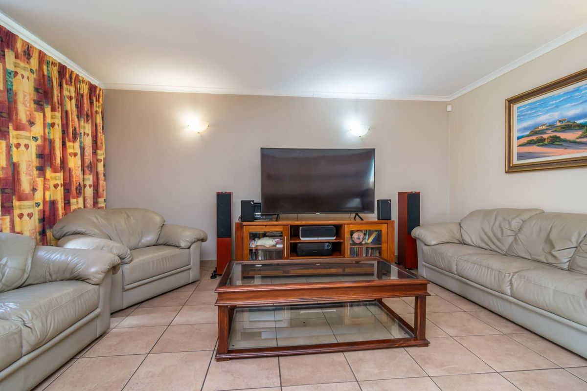 A comfortable living room featuring neutral wall tones, tiled flooring, and wall-mounted lighting fixtures, providing a functional and inviting space for relaxation.