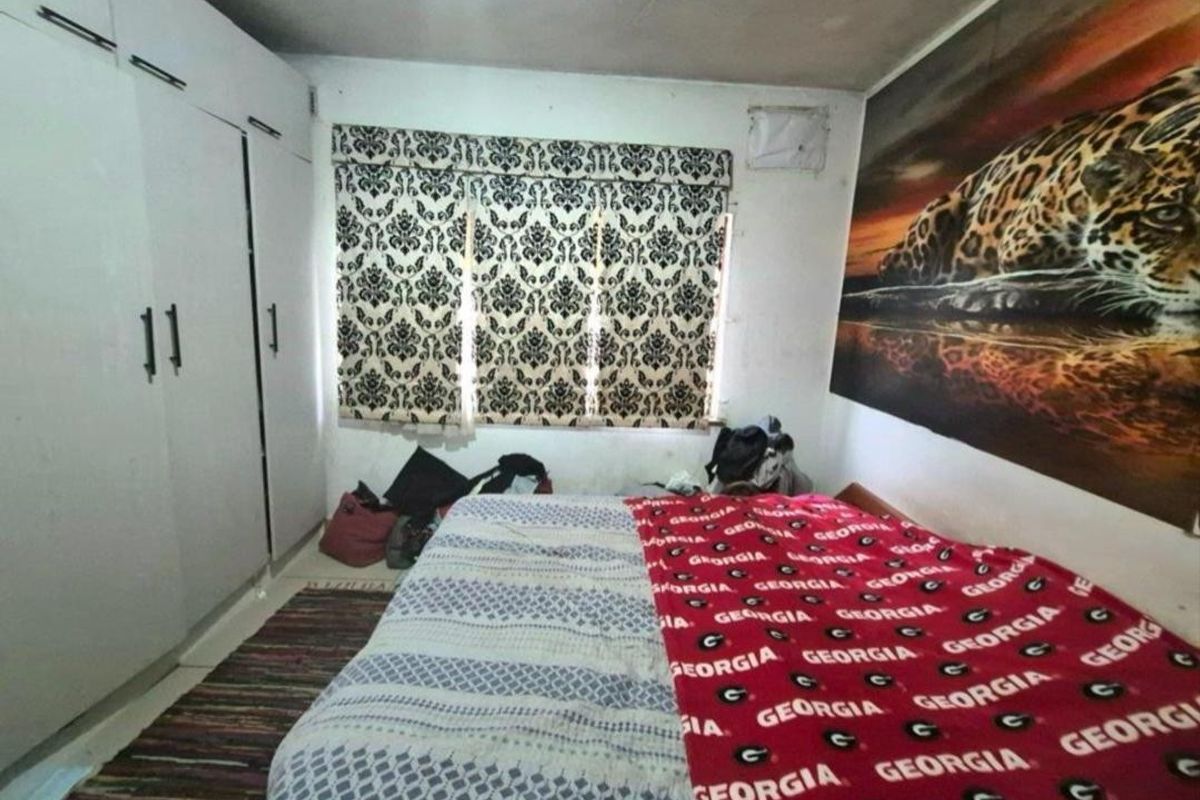 A bedroom featuring built-in cupboards and window blinds, requiring cosmetic updates to the ceiling and wall finishes to improve its overall condition.