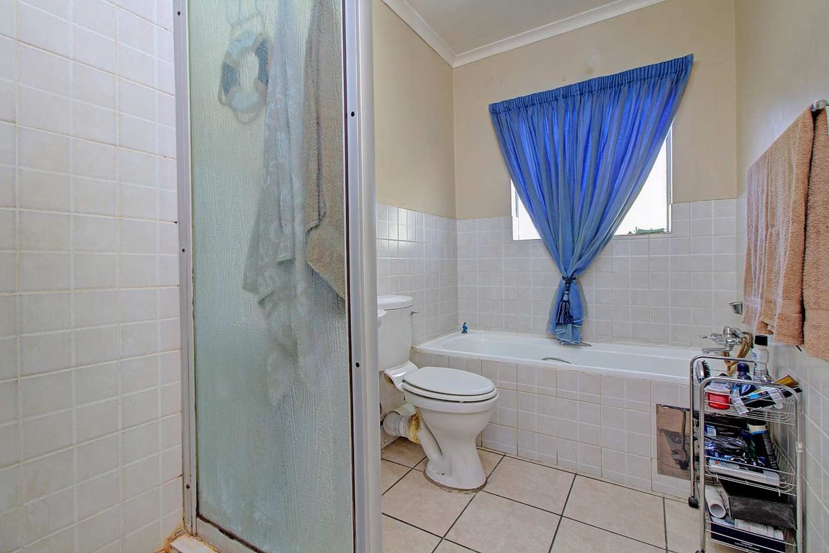 A dated bathroom featuring a shower cubicle, a built-in bathtub with tiled surround, and a standard toilet.