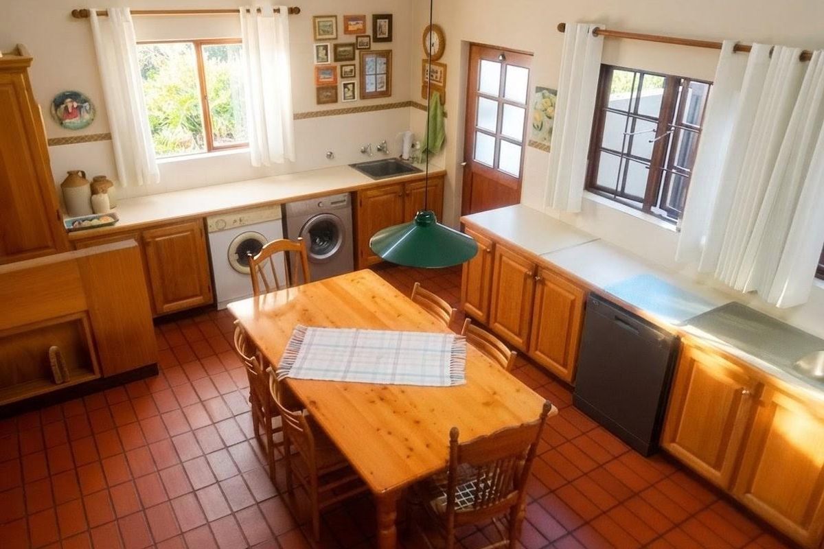 A spacious kitchen featuring traditional wooden cabinetry, terracotta tiled flooring, and ample natural light from multiple timber-framed windows.