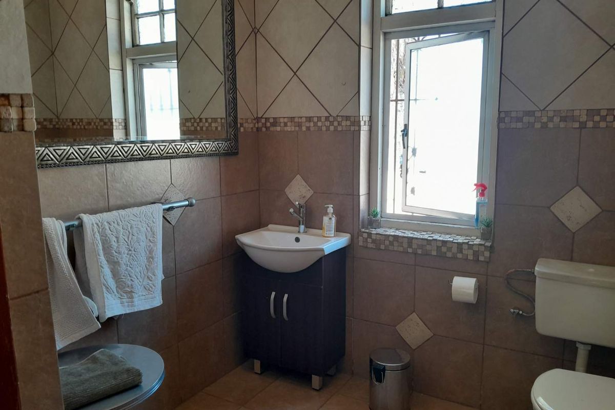 A functional bathroom featuring tiled walls and flooring, a vanity cabinet with a basin, and a standard toilet.