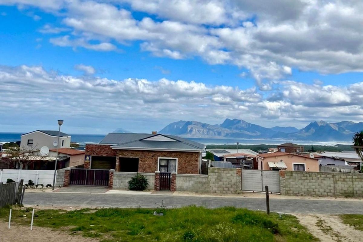 A scenic elevated view overlooking a residential neighborhood with a prominent mountain range and ocean backdrop.