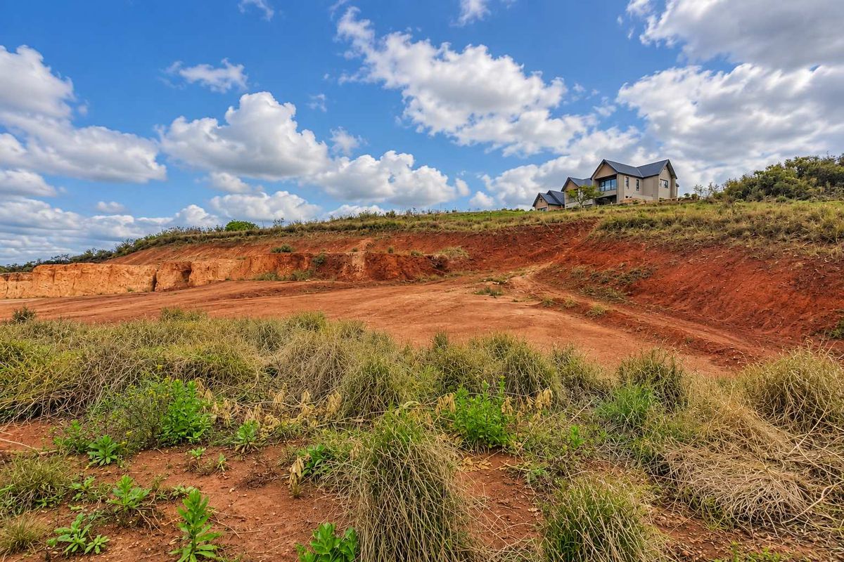 A view of a vacant commercial land plot featuring excavated earth banks and natural sloped terrain with surrounding vegetation.