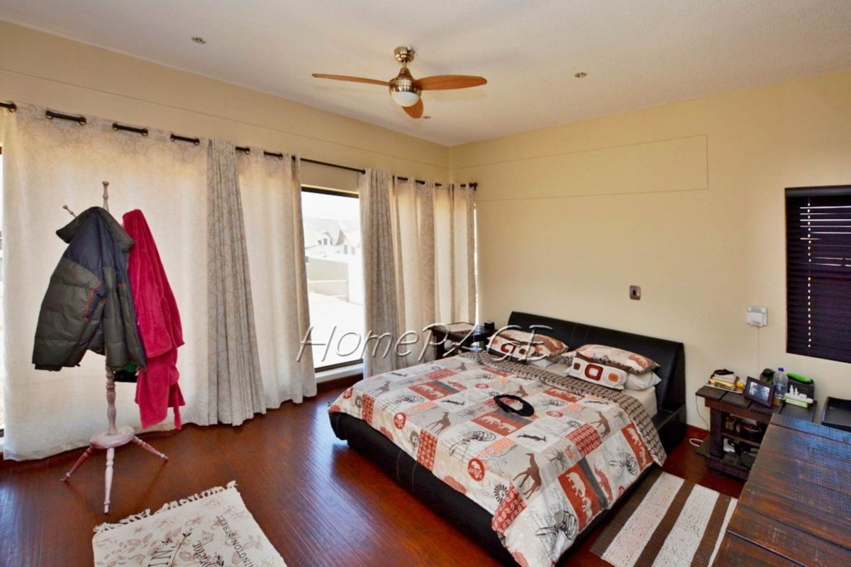 Spacious bedroom featuring dark wood-look flooring, a ceiling fan, and large sliding glass doors providing access to the exterior.