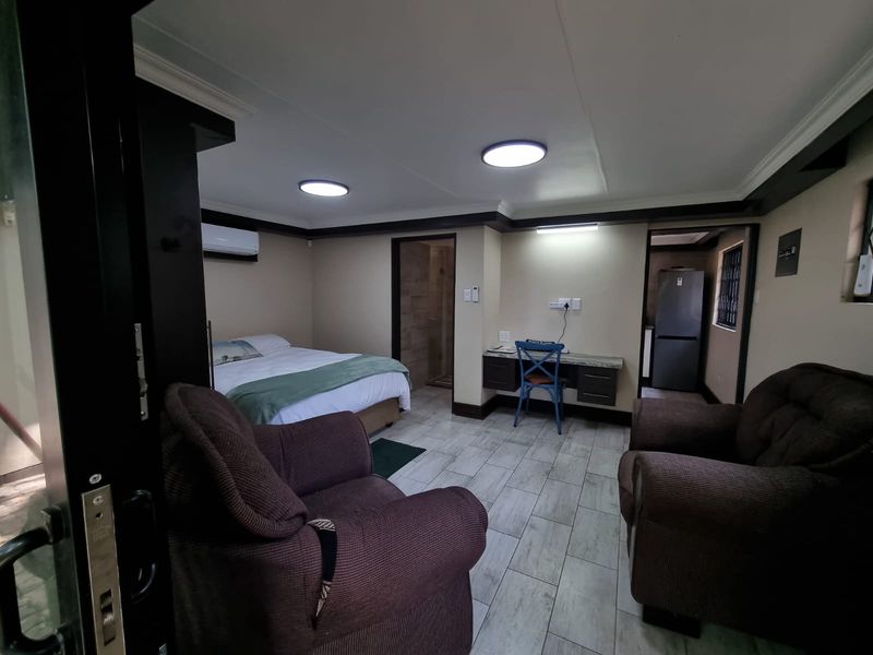 A well-maintained bedroom featuring tiled flooring, built-in desk space, air conditioning, and direct access to an en-suite bathroom.