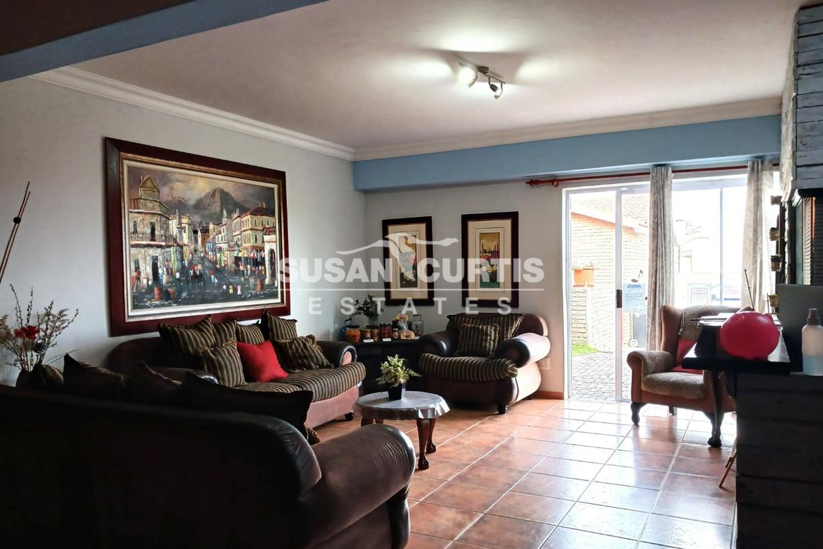 A spacious living room featuring tiled flooring, crown molding, and sliding glass doors providing direct access to the exterior.