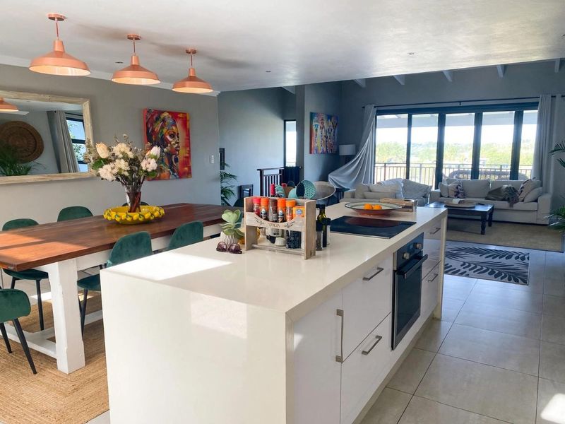 Spacious open-plan living area featuring a modern kitchen island with built-in appliances, dining space, and large sliding doors leading to an outdoor area.