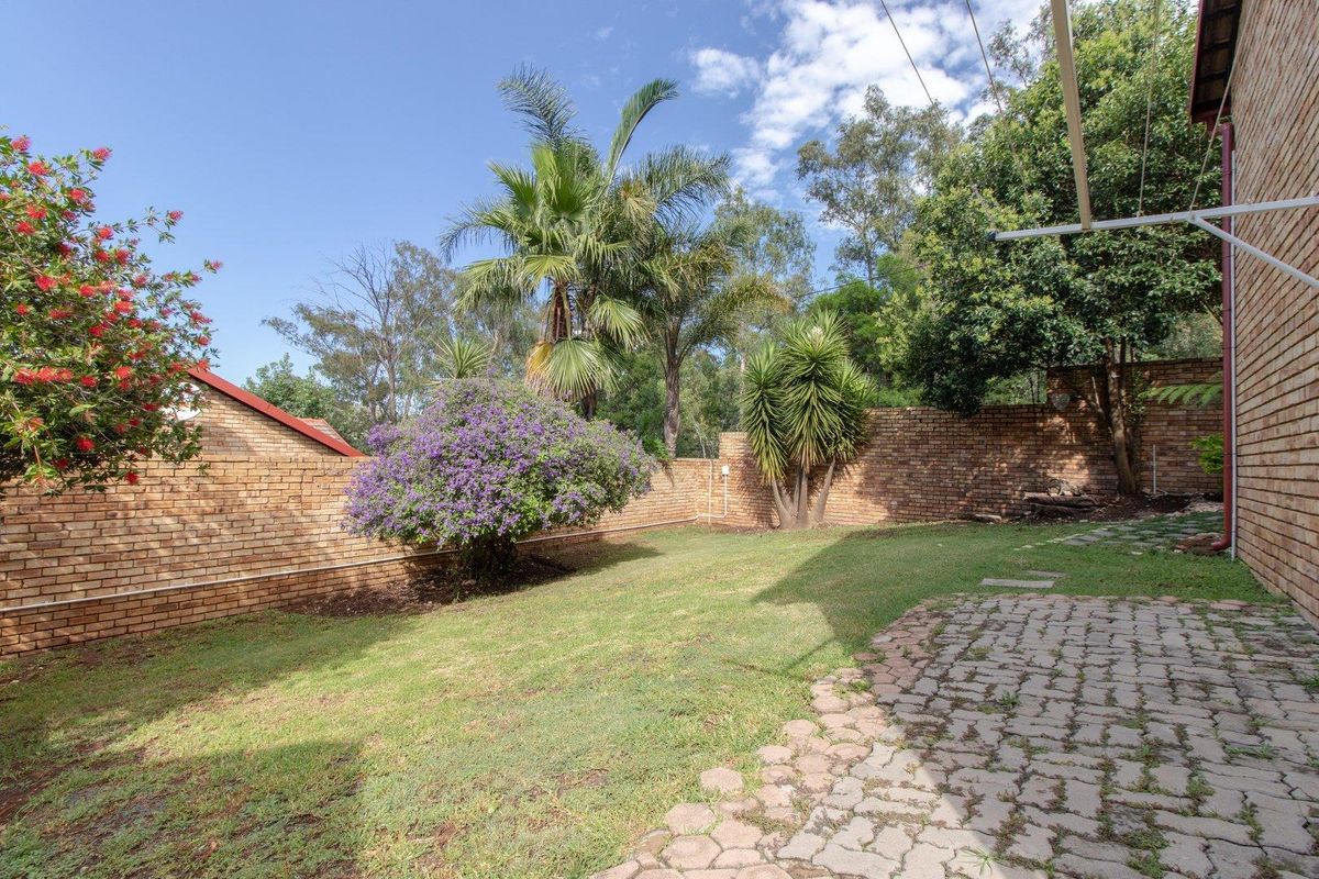 A private rear garden featuring a brick boundary wall, a paved patio area, and established landscaping.
