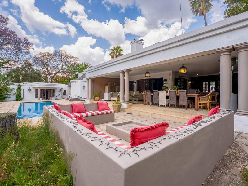 Spacious covered patio area featuring a built-in fire pit, stone paving, and direct access to the swimming pool and garden.