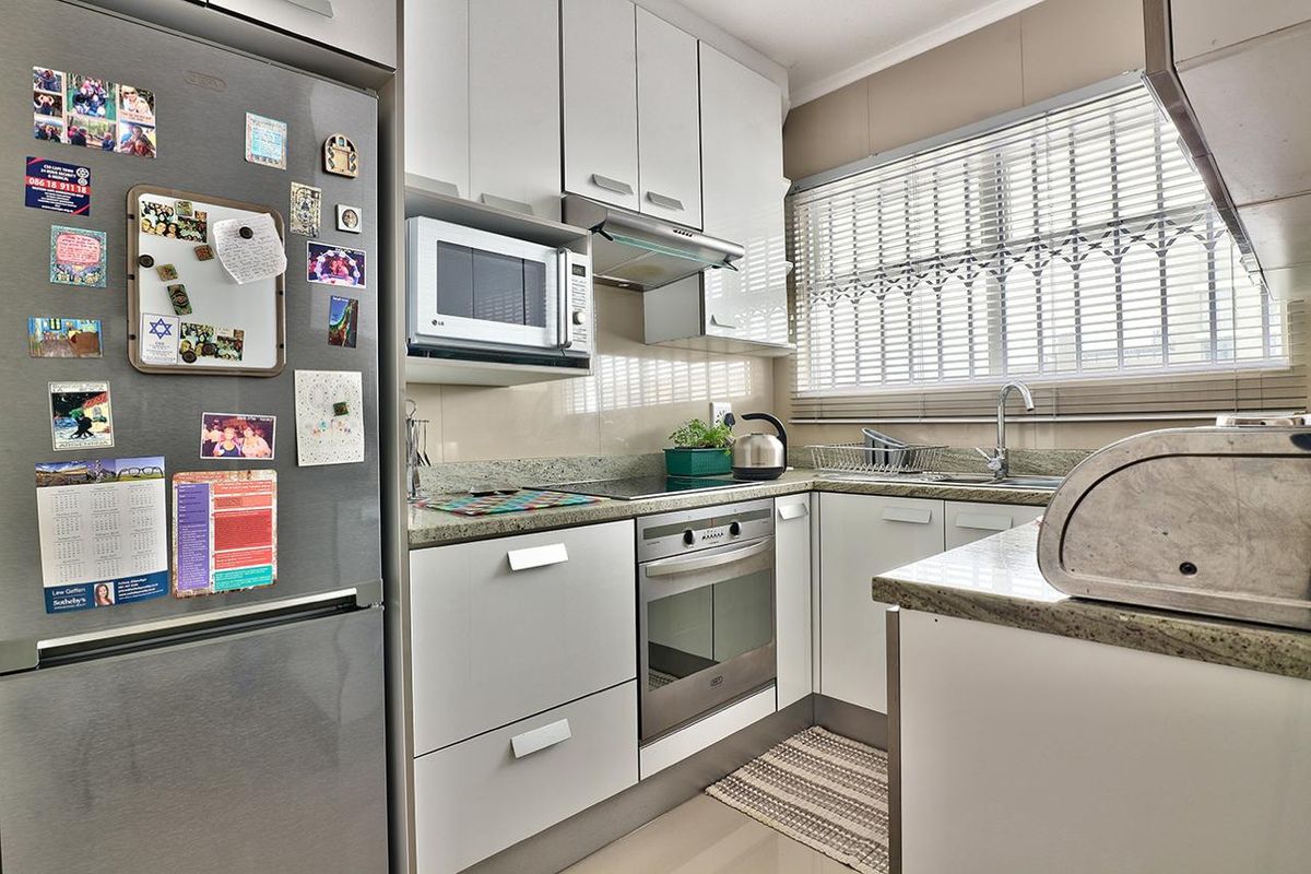 Compact, well-maintained kitchen featuring modern white cabinetry, granite countertops, integrated stainless steel appliances, and a functional layout with ample storage.