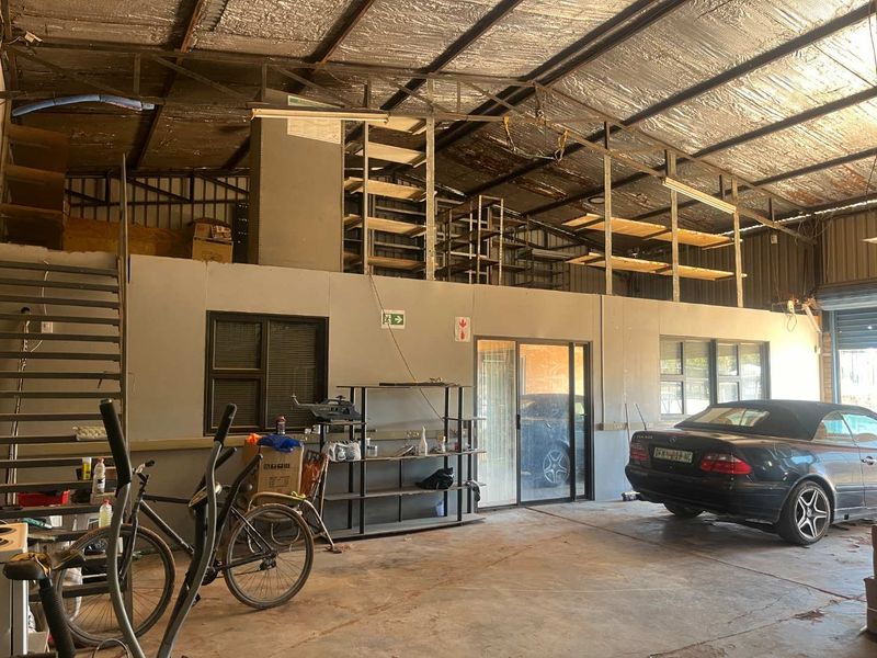 Spacious industrial garage featuring a mezzanine storage level, concrete flooring, and exposed metal roof structure, suitable for workshop or storage use.