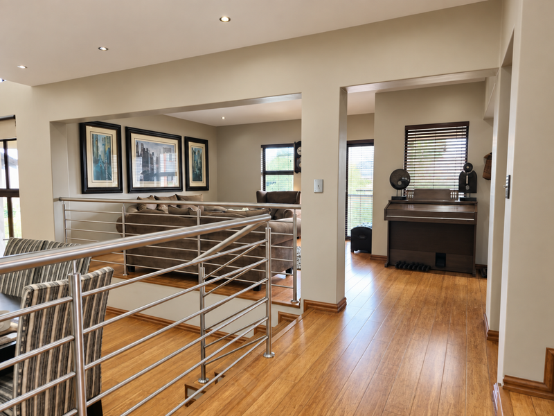 Spacious living area featuring polished timber flooring, modern stainless steel balustrades, and recessed downlighting, creating an open and well-maintained interior space.