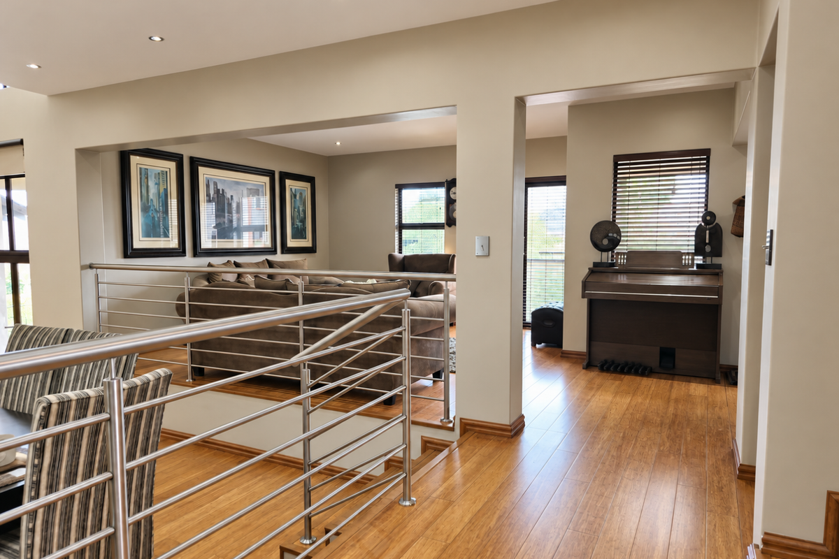Spacious living area featuring polished timber flooring, modern stainless steel balustrades, and recessed downlighting, creating an open and well-maintained interior space.