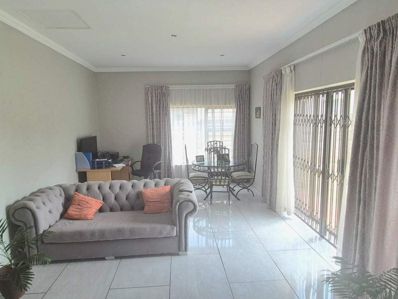 A spacious living area featuring neutral walls, polished tiled flooring, and large sliding glass doors that provide access to the exterior.