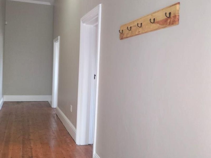 A clean, well-maintained hallway featuring polished timber flooring, neutral wall tones, and classic beadboard ceiling detailing.