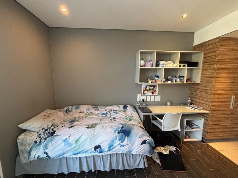 A functional bedroom featuring built-in cabinetry, a desk area, recessed lighting, and tiled flooring, providing a compact and organized living space.