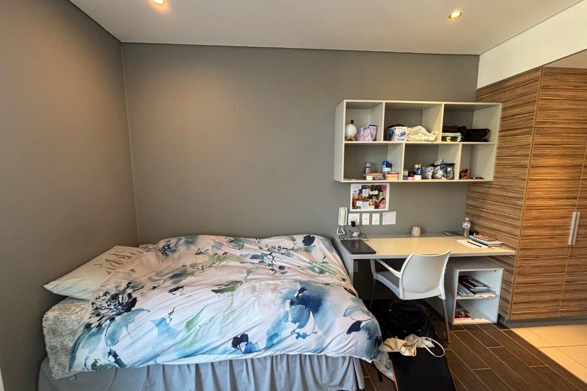 A functional bedroom featuring built-in cabinetry, a desk area, recessed lighting, and tiled flooring, providing a compact and organized living space.