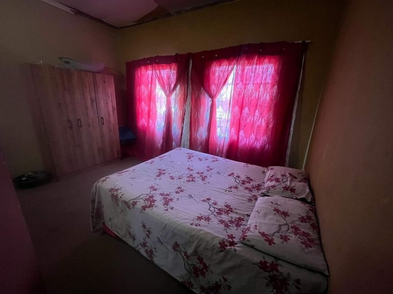 A bedroom featuring a built-in wardrobe, showing signs of wear including damaged ceiling and wall finishes.