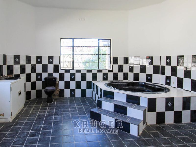 Spacious bathroom featuring a sunken bathtub, tiled vanity with integrated sink, and a toilet, finished with a distinctive black and white checkered tile scheme.