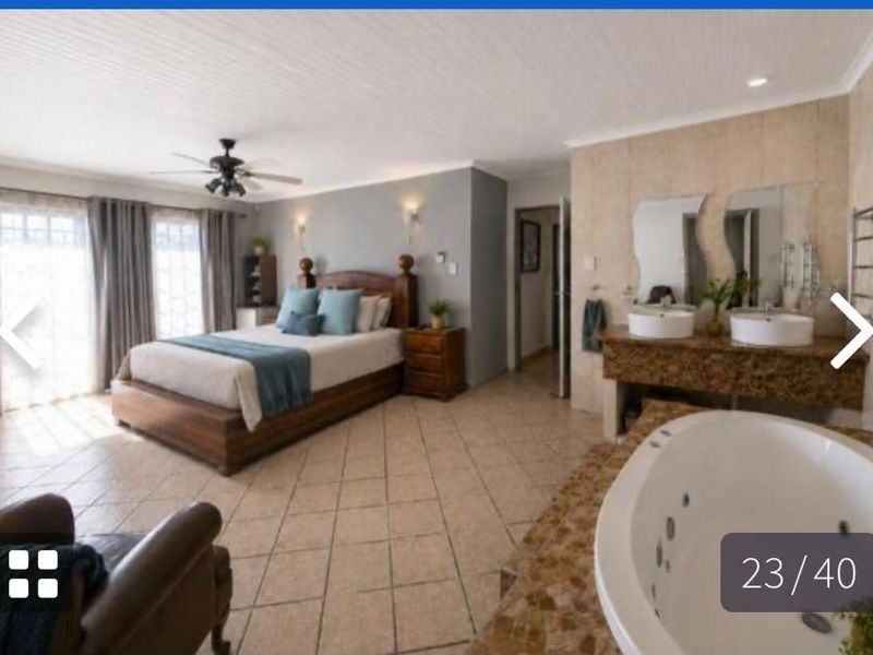 Spacious open-plan bedroom featuring an integrated en-suite bathroom with a jetted tub, dual vanity, and tiled flooring throughout.