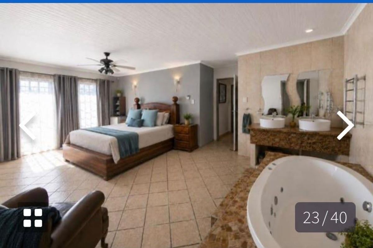 Spacious open-plan bedroom featuring an integrated en-suite bathroom with a jetted tub, dual vanity, and tiled flooring throughout.
