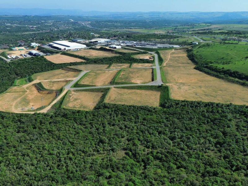 Aerial view of a large industrial development site featuring cleared land plots, paved access roads, and surrounding natural landscape.