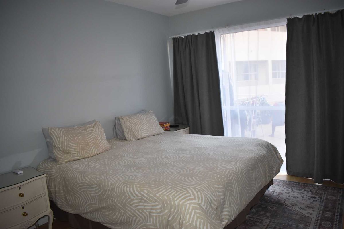 A bedroom featuring neutral wall tones, large window with curtain treatments, and access to an outdoor area.