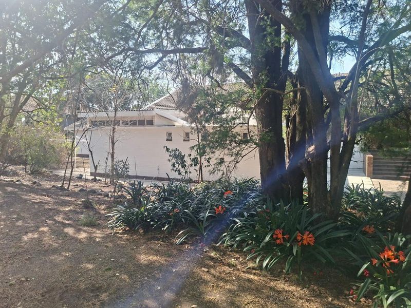 A view of the rear exterior of the house, featuring a tiled roof, brick walls, and a mature, landscaped garden area.